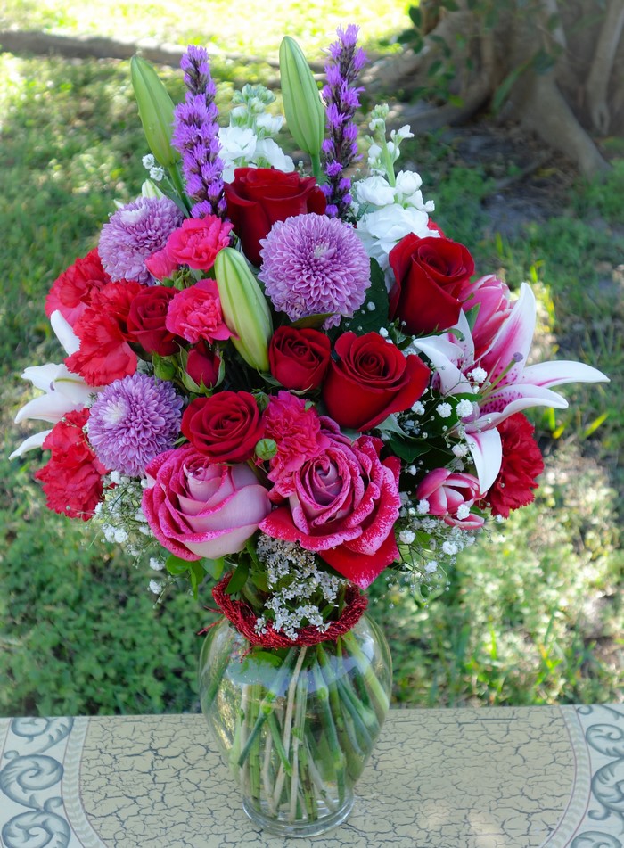 Vase of red and pink roses, lilies, and purple flowers