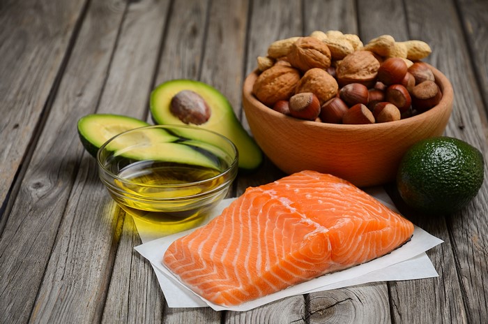 Salmon, Avocado, Nuts, and Oil on Wooden Table
