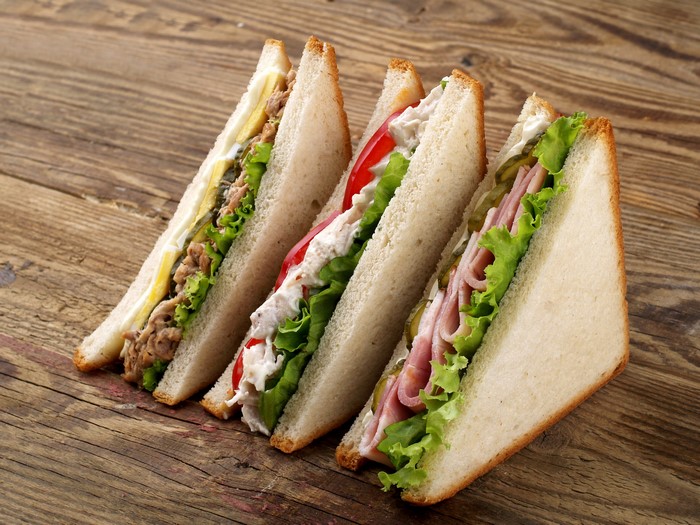 Four sandwiches on a wooden table