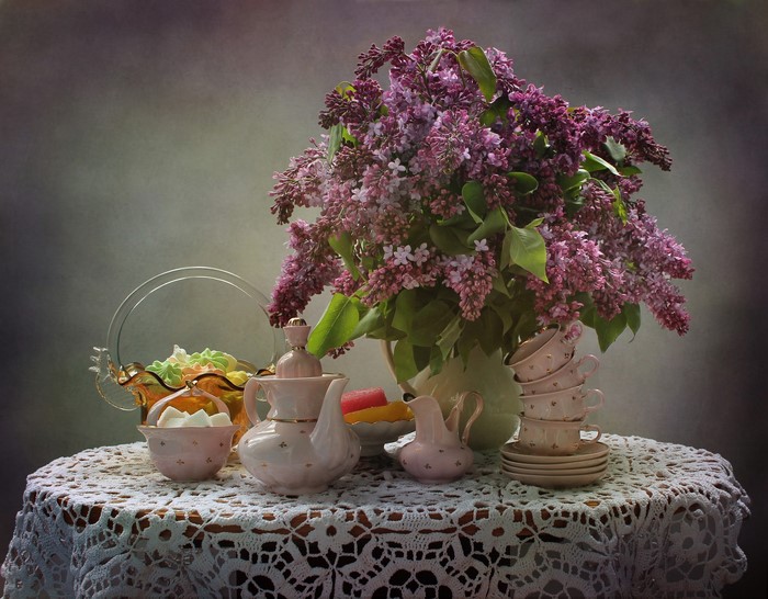 Still-life with lilac bouquet, tea set, and sweets