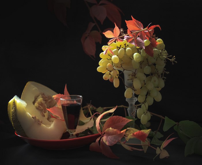 Still life with grapes, melon, wine, and autumn leaves