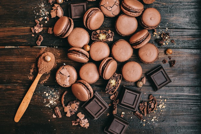 Chocolate macarons and chocolate squares on a wooden table