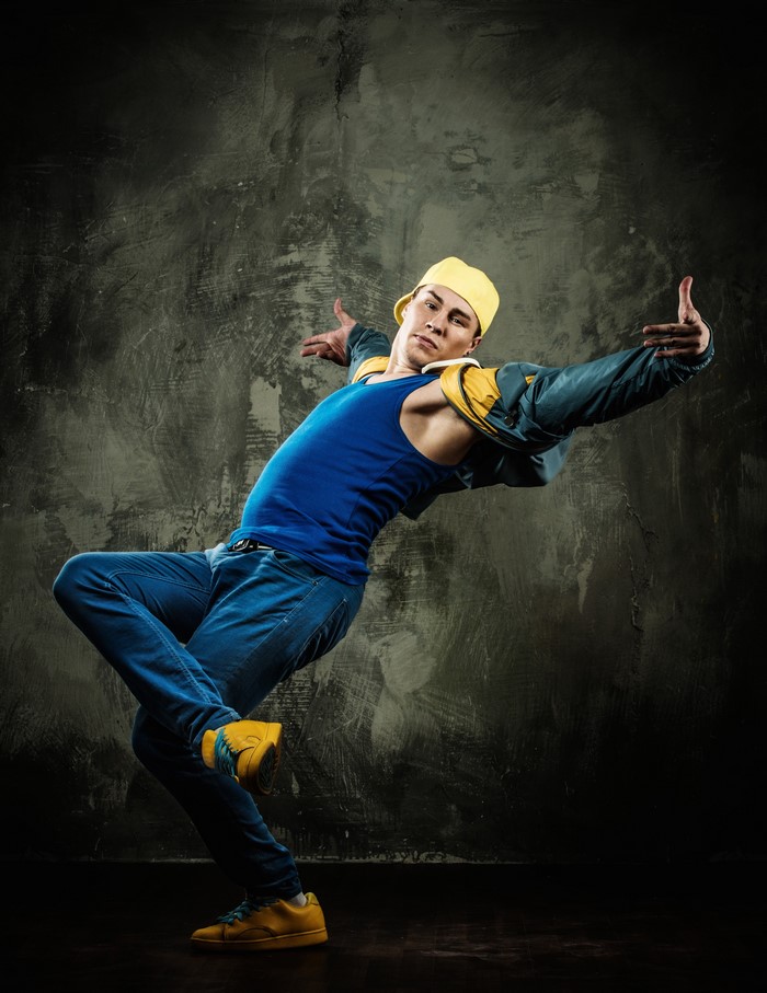 Man in blue tank top and yellow cap dancing
