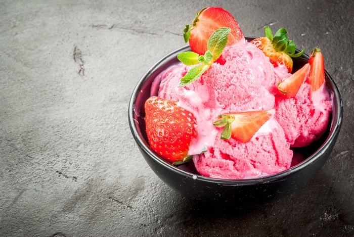 Strawberry ice cream in a bowl with fresh strawberries