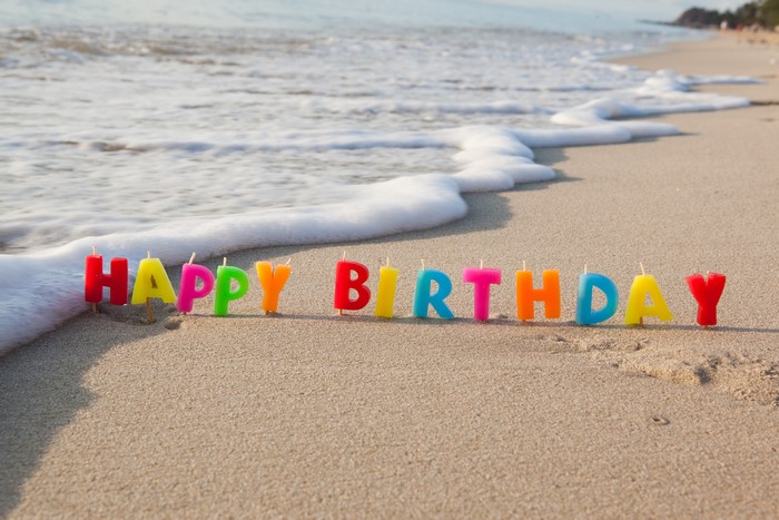 Happy Birthday candles on a beach with waves