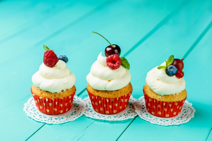 Three cupcakes with berries and cream