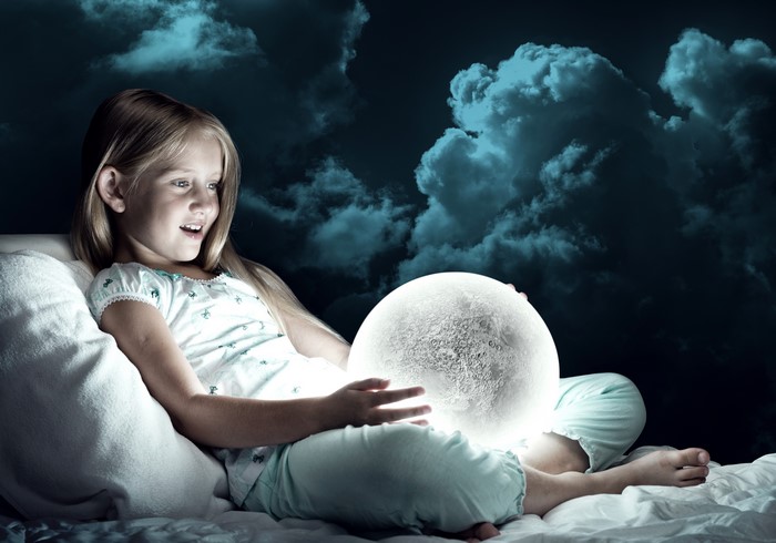 Little girl with a glowing moon ball at night