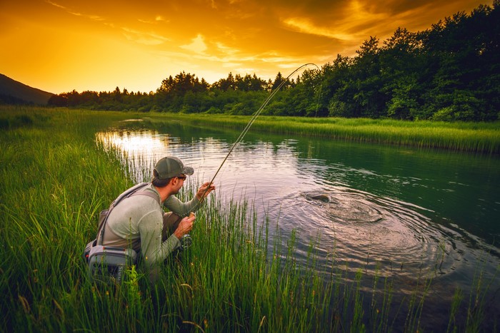 Man fishing in a river at sunset