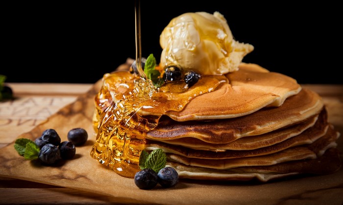 Stack of pancakes with ice cream, blueberries, and honey