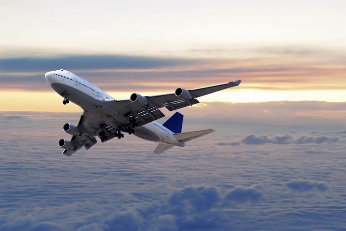 Airplane flying above clouds at sunset