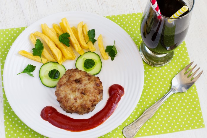 Creative meal with french fries, meat, cucumbers, and drink