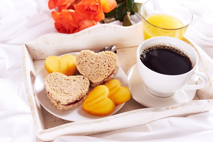 Breakfast tray with coffee, juice, heart sandwiches, and roses