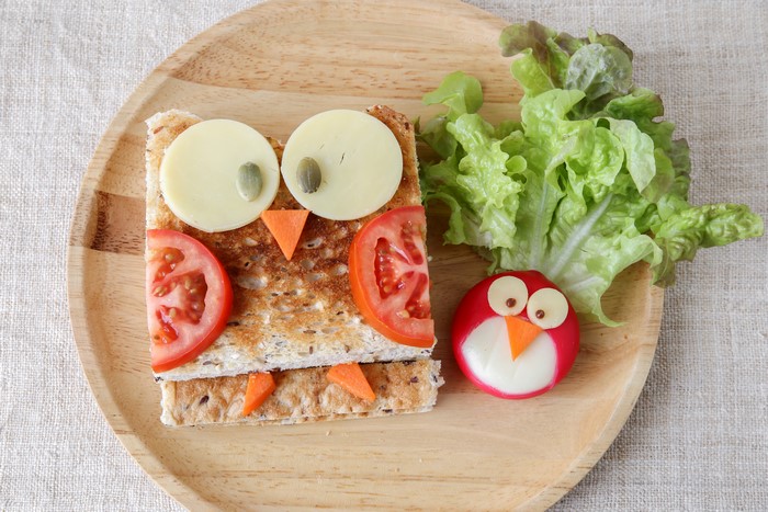 Creative owl sandwich with vegetables and cheese on cutting board