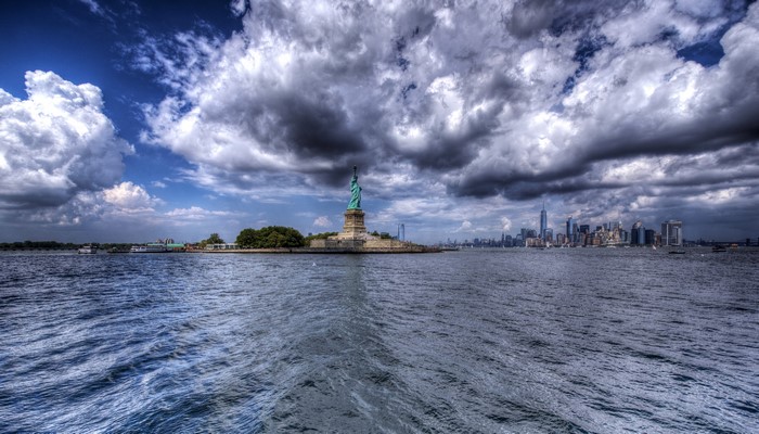 Statue of Liberty and New York City Skyline under Clouds