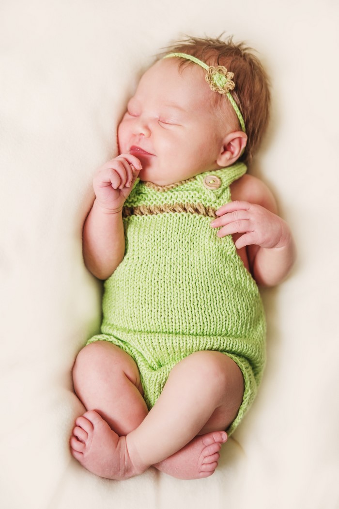 Newborn baby girl sleeping in a green romper