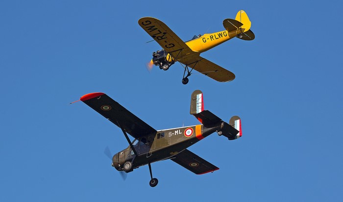 Two vintage airplanes flying in the sky