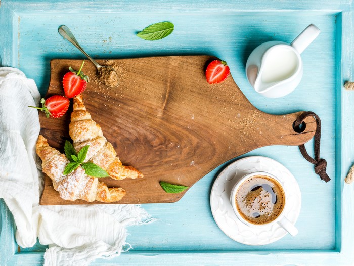 Croissants with Strawberries, Coffee, and Milk on a Cutting Board