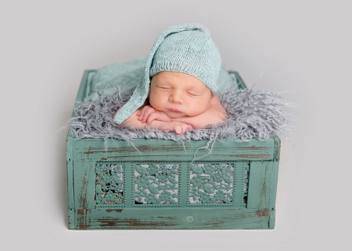 Newborn baby sleeping in a teal wooden box
