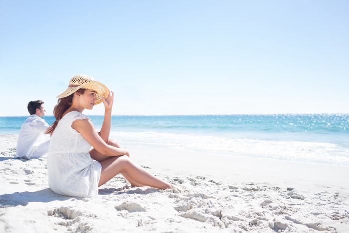 Couple Sitting on Beach with Ocean Background