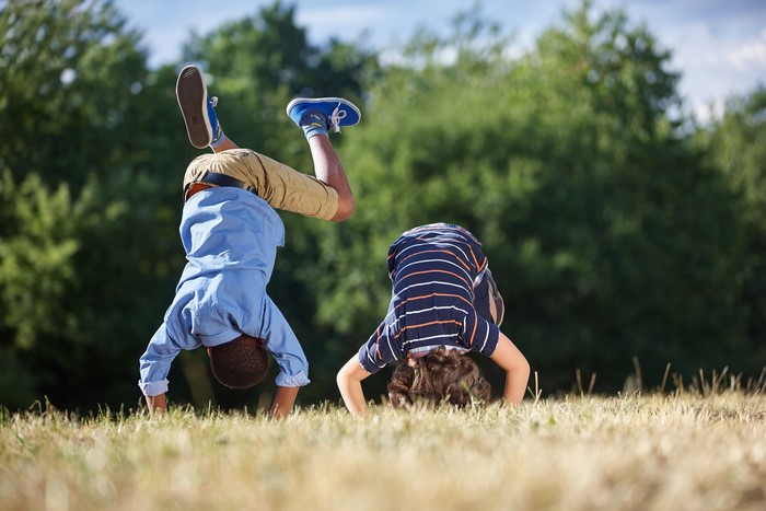 Two Boys Doing Handstands in a Field