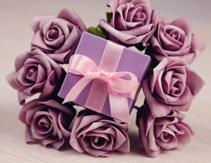 Purple roses and a gift box with a pink bow