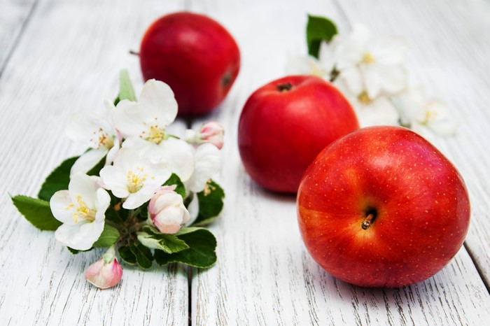Red apples and apple blossoms on wooden planks