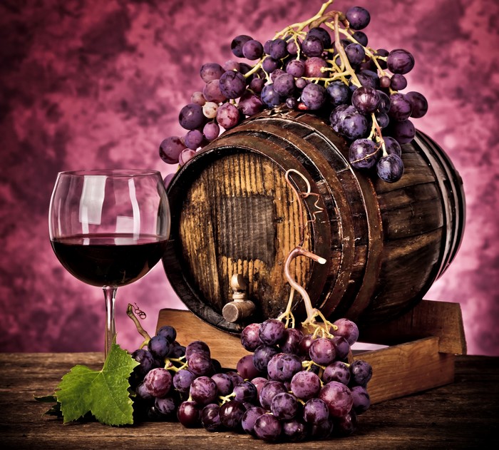 Wine barrel with grapes and glass of red wine