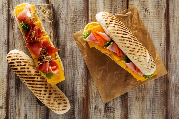 Two sandwiches with ham and cheese on wooden planks