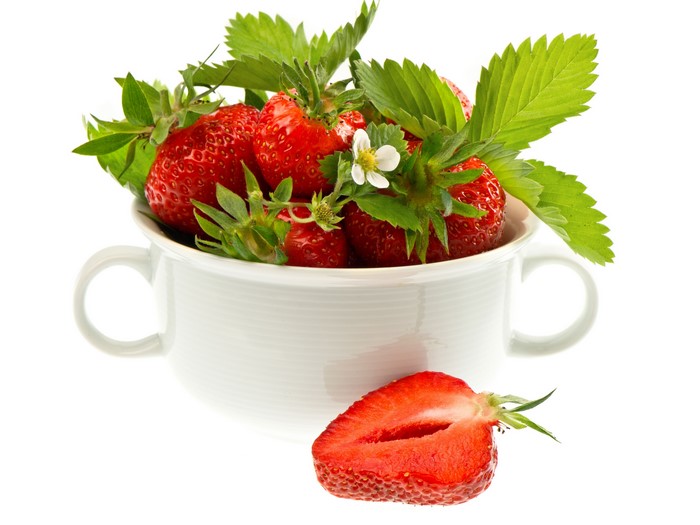 Strawberries in a white cup with foliage