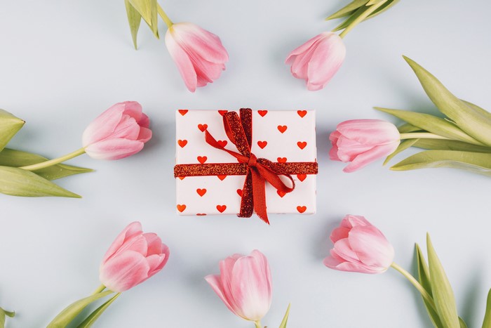 Gift box with pink tulips on a colored background