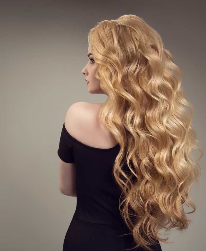 Woman with long blonde curly hair in black dress