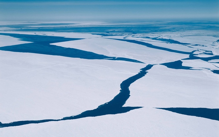 Cracked ice floes on the ocean under a clear sky
