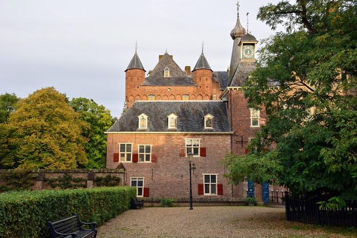Doorwerth Castle with street lights, shrubs, and bench in Netherlands