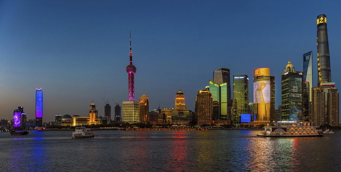Shanghai skyline at dusk with boats on the river