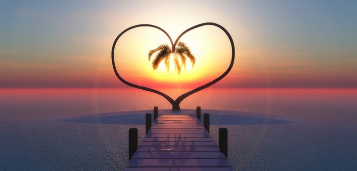 Heart shaped arch with palm tree at sunset over the ocean