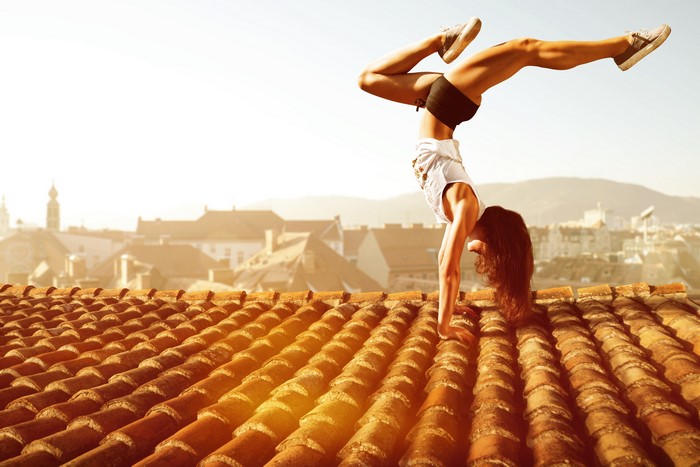 Woman doing a handstand on a tiled roof