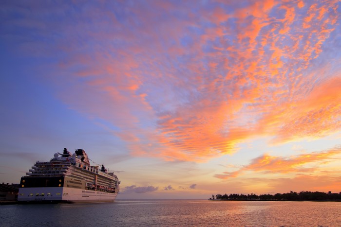 Cruise liner docked at sunset with colorful clouds