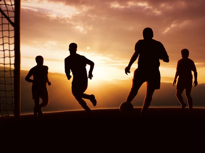 Silhouettes of men playing soccer at sunset