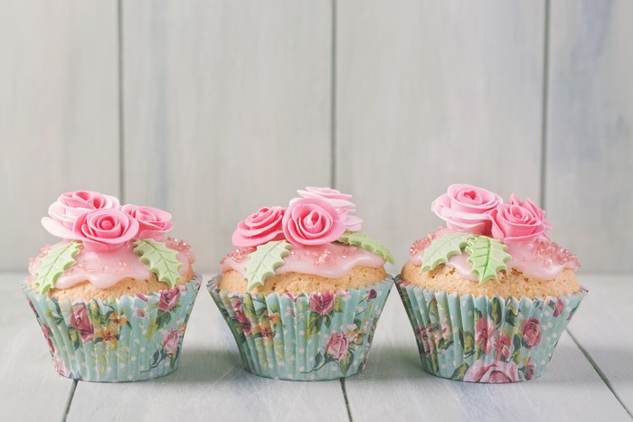 Three cupcakes with pink roses and green leaves
