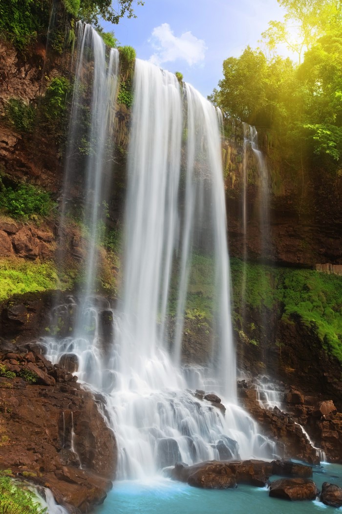 Waterfall cascading over rocky cliffs with lush greenery