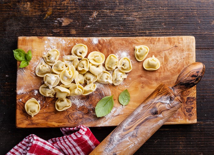 Fresh Pelmeni on a Wooden Cutting Board with Basil
