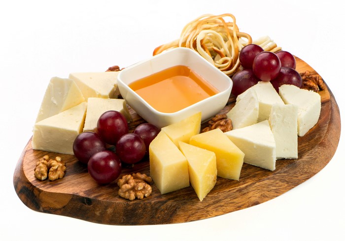 Cheese board with grapes, nuts, and honey