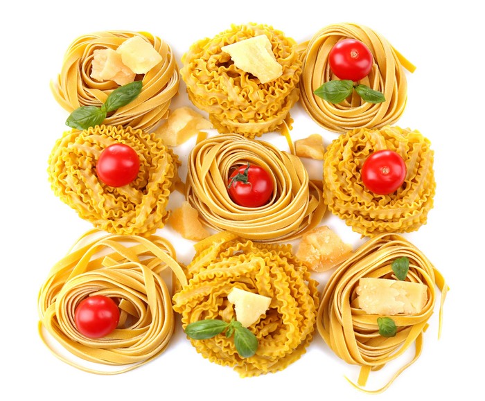 Pasta nests with tomatoes, cheese, and basil on white background