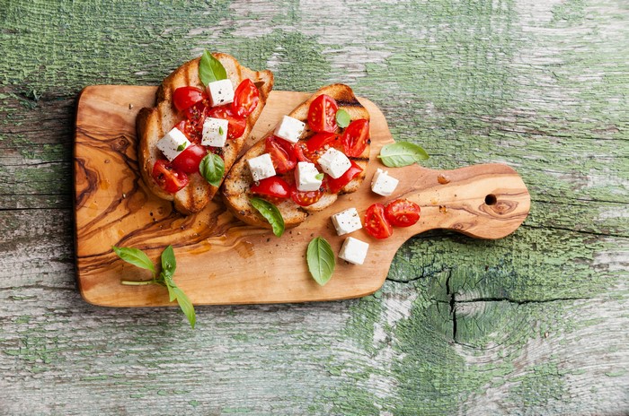 Bruschetta with tomatoes and feta cheese on a cutting board