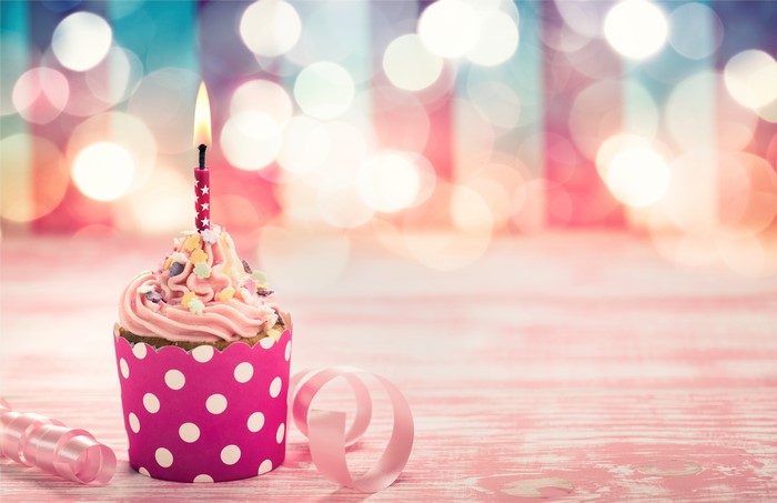Birthday cupcake with lit candle and ribbon