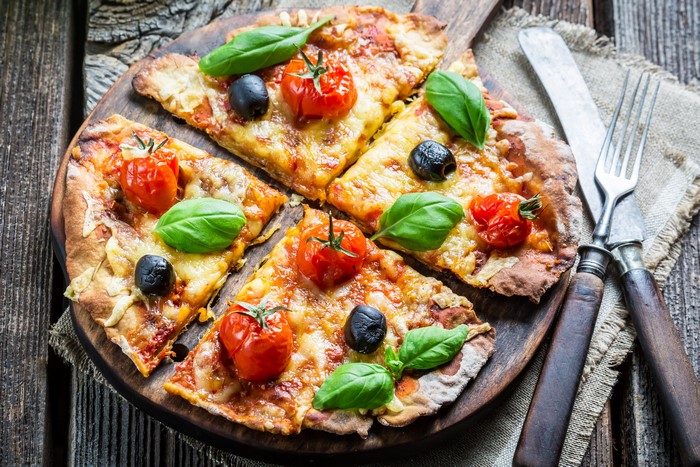 Pizza with Tomatoes, Olives, and Basil on a Wooden Board
