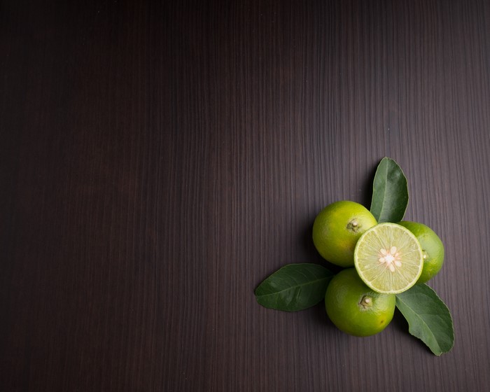 4K Fresh Green Limes with Leaves on Wood
