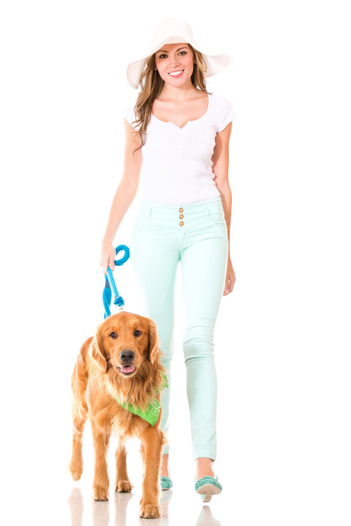 Woman in hat walking a golden retriever dog