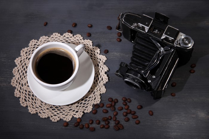 Coffee cup and vintage camera with coffee beans