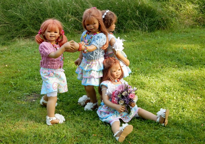 Four dolls in a park with grass and flowers